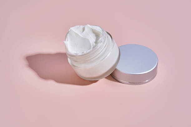 istock An open jar of cream with its texture on a pink background. 2225136102