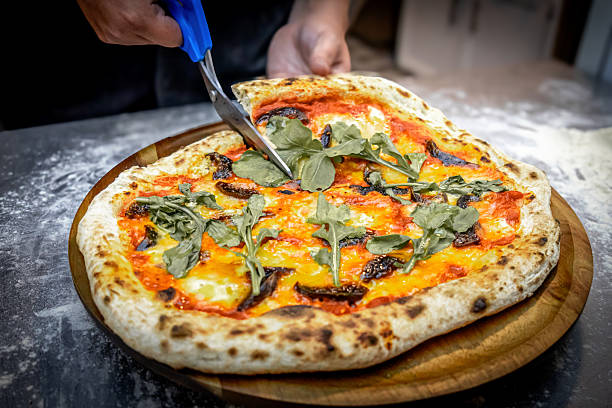 istock Freshly baked fig pizza with a golden, crispy crust, being cut into slices with scissors. 2225136373