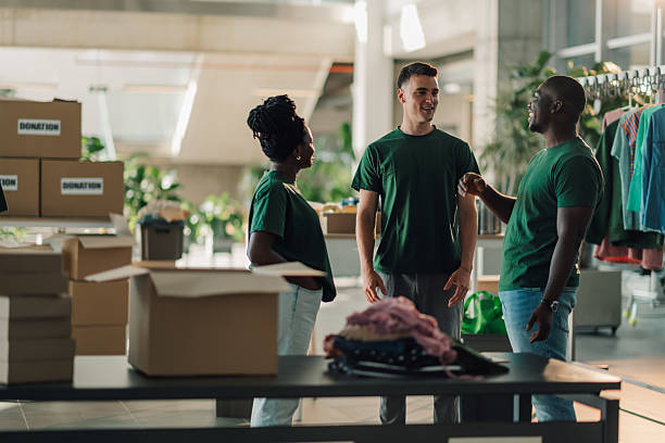 istock Volunteers chatting while sorting donated clothes in charity shop 2225137408