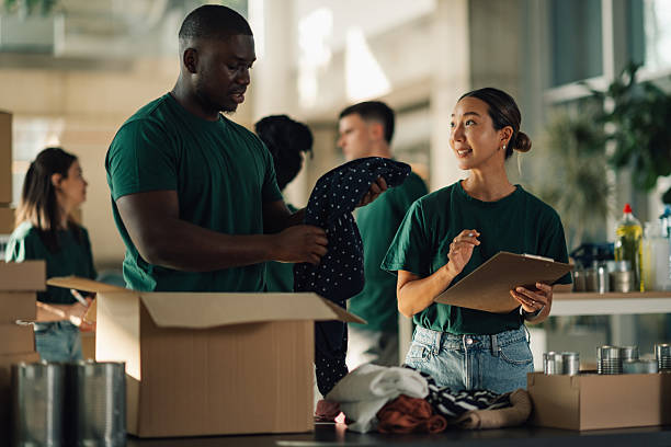 istock Volunteers sorting clothes and food in cardboard boxes for donation 2225137565