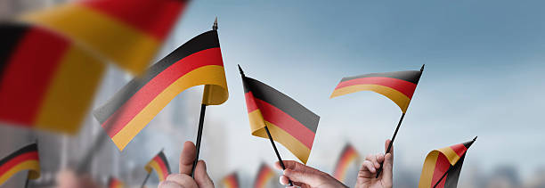 istock Germany flags in their hands on a blurred urban background 2225139532
