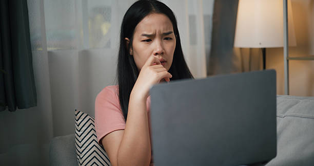 istock Stressed woman working on laptop with serious expression on sofa at home. 2225144349