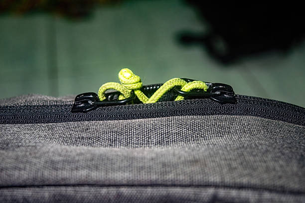 Close up of backpack zipper featuring vibrant green cord threaded through dark pulls, highlighting rugged design, travel utility, and contrast rich detail for everyday gear themes