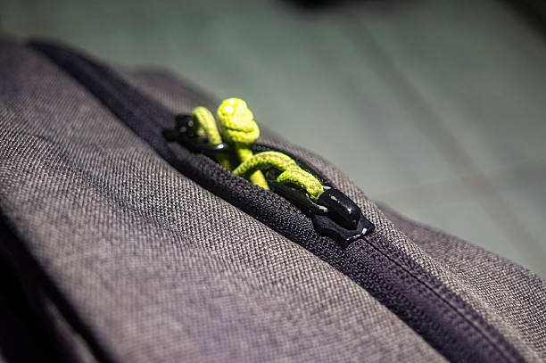 istock Close up of backpack zipper with green pull cords against gray fabric, showing durable design, urban utility, and stylish outdoor ready gear. Great for travel or active lifestyles 2225146015