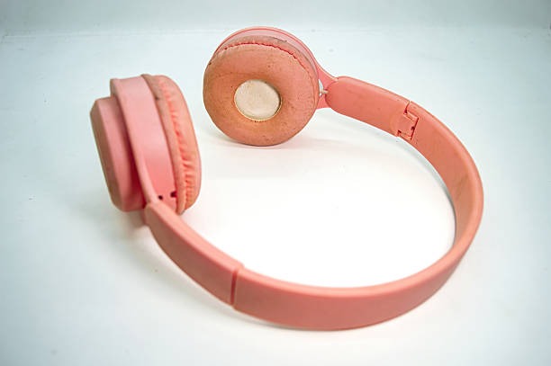 Pink headphones with worn ear cushions placed on a white surface, capturing softness, wear, and casual realism. Great for tech, audio gear, and lifestyle usage themes