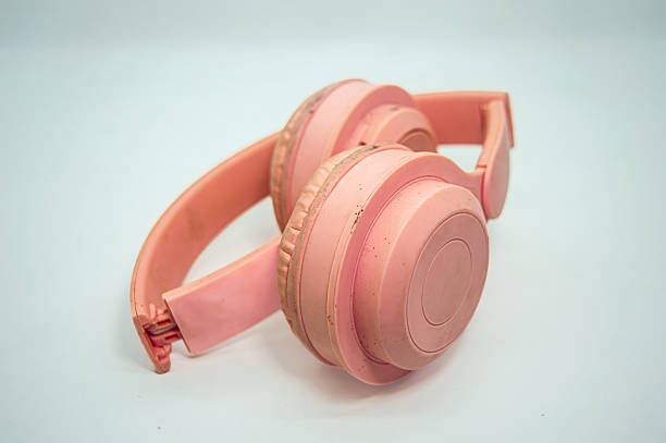 istock Worn pink headphones with a broken headband placed on white background, highlighting damage, texture, and nostalgic tech appeal. Ideal for themes of repair, reuse, or retro gear 2225146684