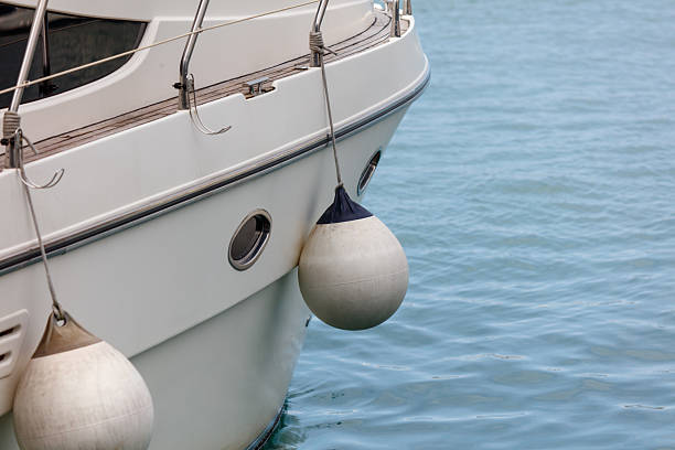 A white boat with a blue and white buoy attached to it. The buoy is in the water and the boat is in the water