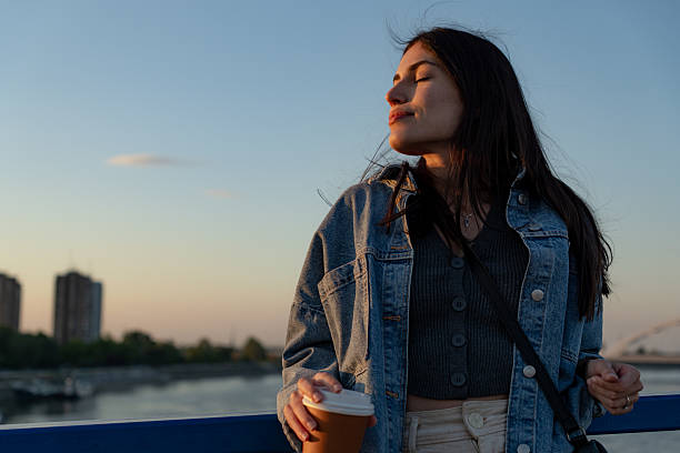 istock Young Woman Enjoying a Coffee Break on a Bridge at Sunset 2225153034