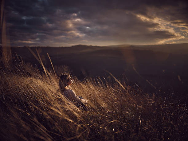 Smiling woman relaxing in tall grass during autumn day on a hill. Photographed in medium format. Copy space.