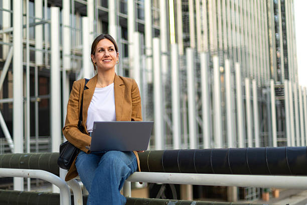 istock Smiling professional woman using laptop outdoors 2225154405