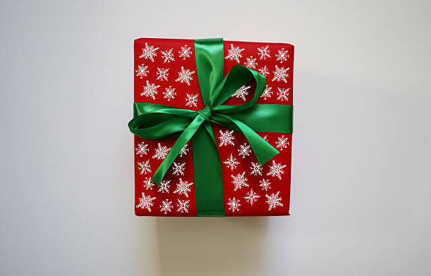 istock Gift isolated on white background. Square red box with green ribbon, bow. Box has white snowflake patterns painted on it 2225156070