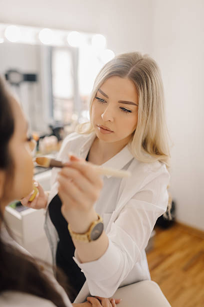 istock Professional makeup artist applying foundation on client's face in beauty salon 2225156449