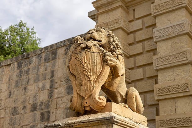 Malta, Mdina - April 15, 2025: Baroque stones lion statue holding coat of arms and guarding Main Gate of Mdina, symbol of strength and nobility at entrance to fortified Silent City