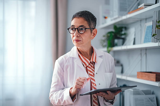 istock Senior Female Doctor Holding Tablet in Modern Office Setting 2225158003