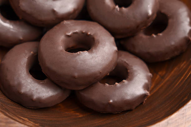 Chocolate donuts in wooden bowl. Sweet baked dessert doughnuts. Close up.