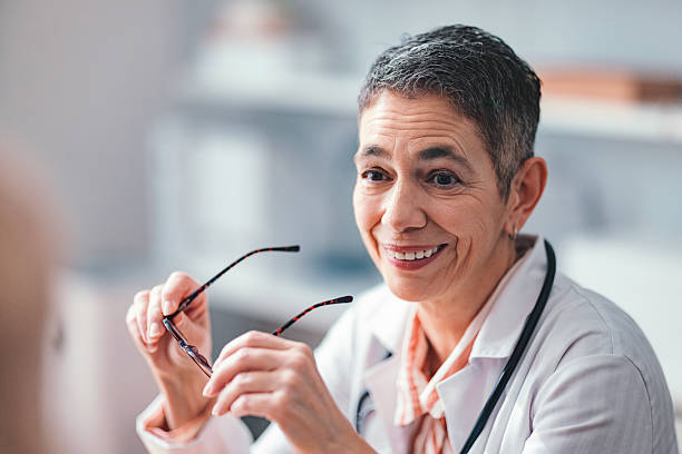 istock Friendly Doctor Smiling and Holding Glasses During a Consultation 2225161916
