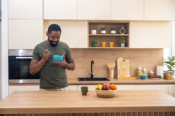 istock Morning routine, simple living. One man standing in the kitchen, drinking coffee, eating healthy breakfast. Male entrepreneur at home, starting his day casual and relaxed. 2225172467