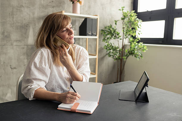 istock Businesswoman talking on phone and taking notes in modern office 2225174323