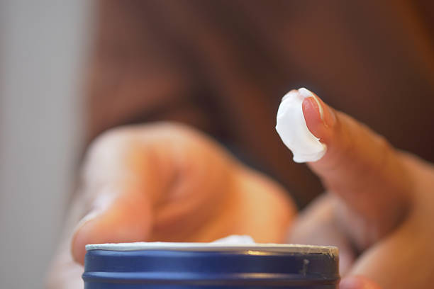 istock Hands are shown applying cream from a container, focusing on skincare 2225177229
