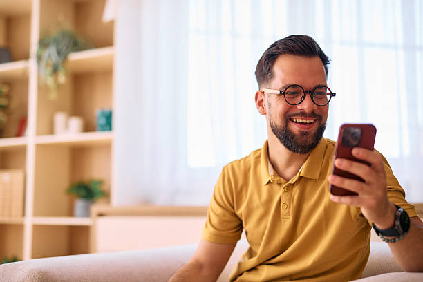 istock Young Man Relaxing on Sofa, Enjoying Funny Content on Smartphone 2225179783