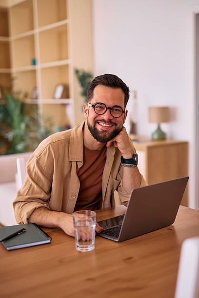 istock Young man working from home smiling and looking at camera 2225180060