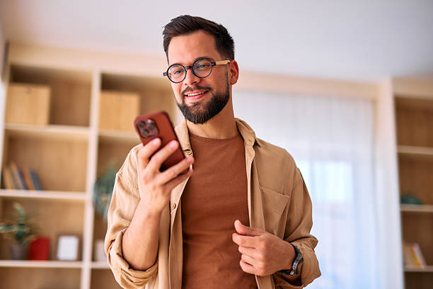 istock Young man using smartphone at home, reading messages and smiling 2225180107