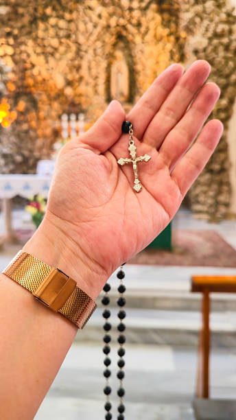 istock Hand holding a black rosary with a cross inside a church 2225181274