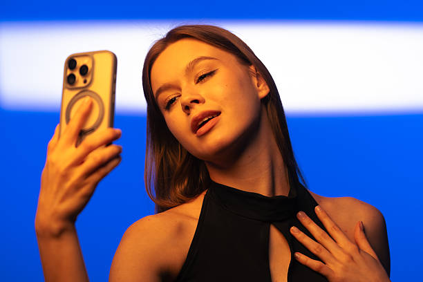 Young Woman Taking Selfie Against Bright Blue Background