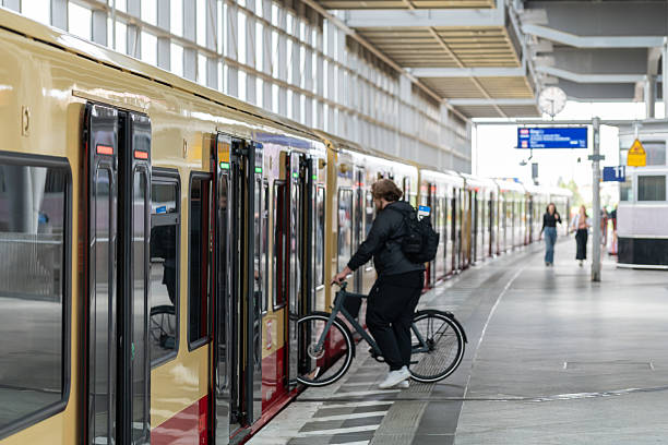Germany, Berlin, Station Südkreuz, July 08, 2025 -Blurred motion of a man with a bicycle gets on a S-Bahn train, two unrecognized people in the background