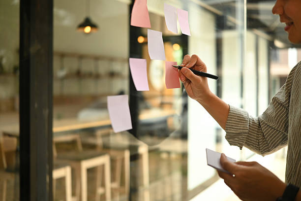 istock Close-up of hands organizing tasks and thoughts with adhesive notes in a creative workspace 2225184022