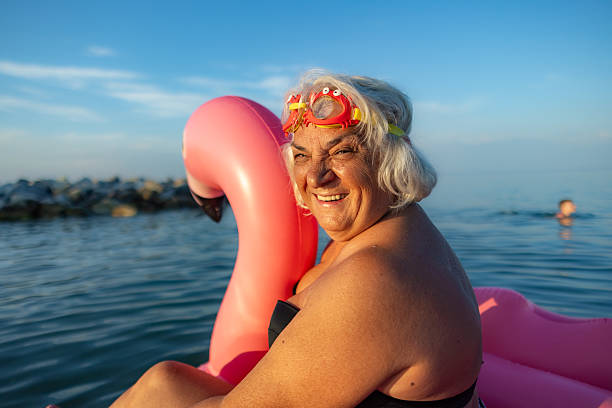 Photo of a senior woman floating in the sea on an inflatable flamingo and enjoying the best years of her life.