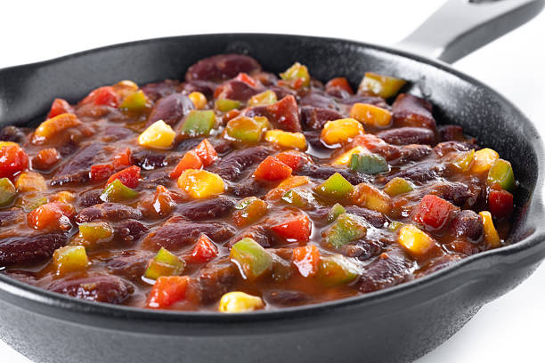 Mexican chilli beans with vegetables in iron pan isolated on white background
