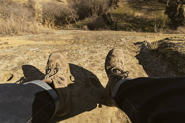 A travelers dusty boots hang over a rugged cliff edge in Georgia as the evening light fades.