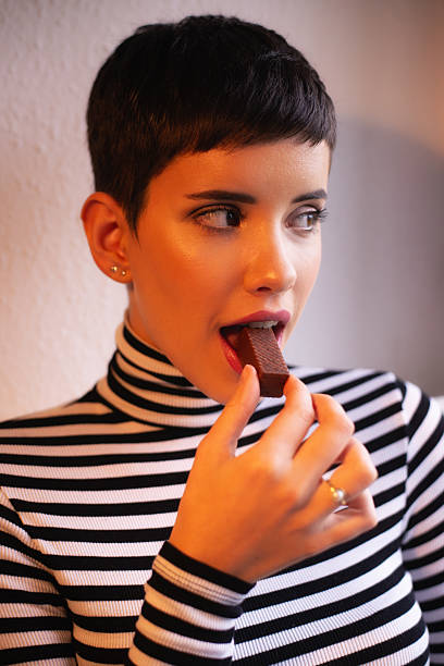 istock Young woman eating chocolate cookie at home 2225197796