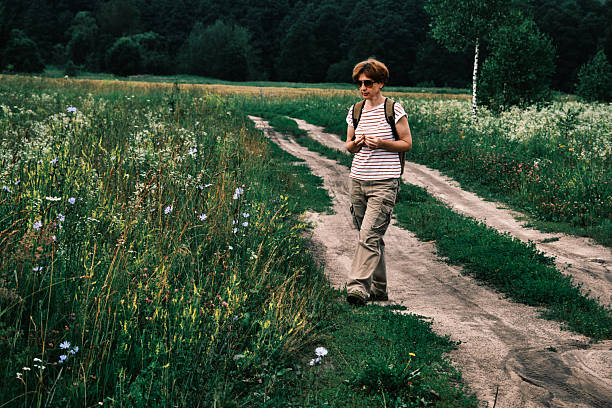 Woman with a summer hat holding a small yellow kitten in the countryside, in summertime