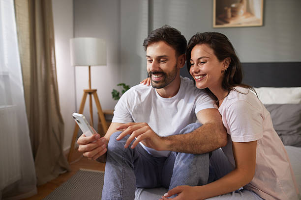 istock Happy couple planning vacation using smartphone in bedroom 2225203829