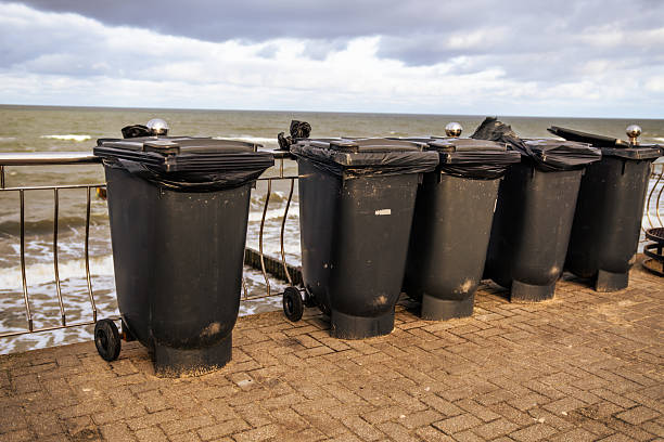 istock Multiple Black Trash Bins Lined Along a Seaside Promenade During a Cloudy Day 2225204792