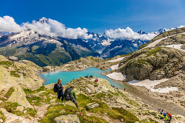Chamonix, France - 08 August, 2024: Happy hiker on the trekking mountain path Tour du Montblanc. Beautiful alpine landscape of the French and Italian Alps. Hikers in the Alps enjoy the nature and mountains