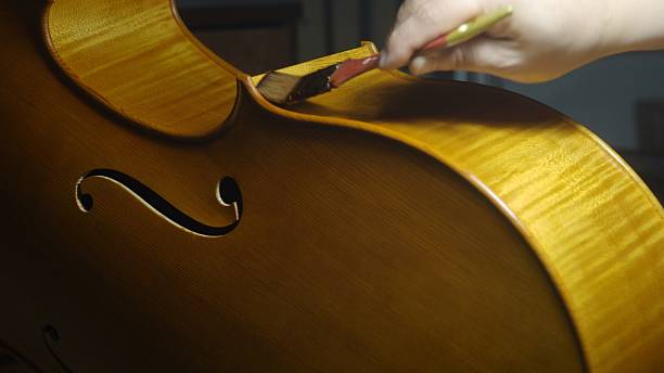 istock Skilled luthier meticulously applying protective varnish to wooden cello surface, utilizing traditional brush technique for optimal sound resonance and aesthetic refinement 2225207652