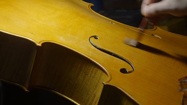 istock Professional luthier carefully applying glossy varnish to wooden cello surface, highlighting intricate craftsmanship of stringed instrument restoration 2225207713