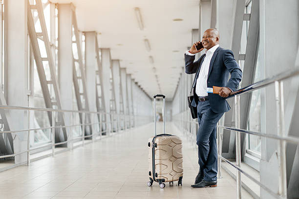 istock Black businessman leaning on railing while talking on the phone at airport 2225208000