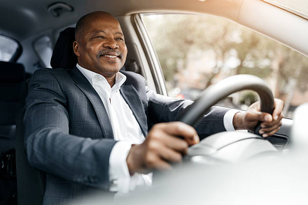 istock Black businessman driving car and smiling while holding steering wheel 2225208541