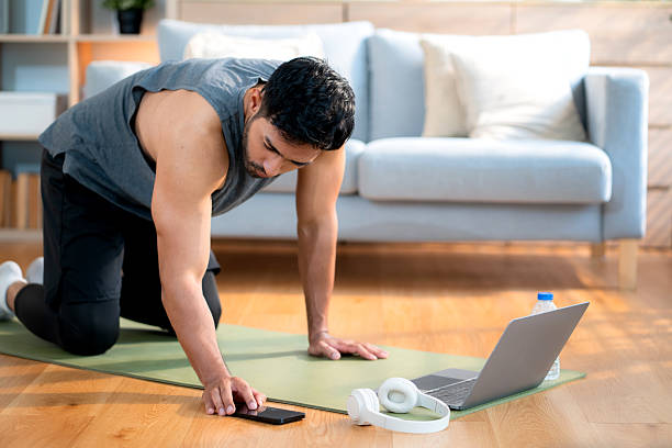 istock Young asian man doing plank exercise in living room at home while watching online workout tutorial on laptop with endurance and motivation, man training plank on yoga mat, digital fitness lifestyle. 2225209235