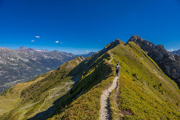 Chamonix, France - 08 August, 2024: Happy hiker on the trekking mountain path Tour du Montblanc. Beautiful alpine landscape of the French and Italian Alps. Hikers in the Alps enjoy the nature and mountains