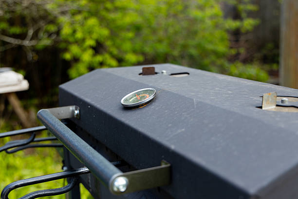Close-up of a grill lid, revealing a thermometer, ready to cook up a delicious summer feast.