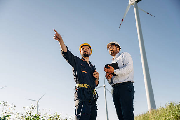istock Making the business. Two men engineers are on field, with wind turbines 2225211159