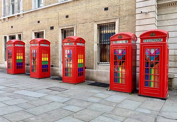 London, UK - June 4, 2025: Five historic classic red telephone boxes in a row displaying LGBTQ + rainbow pride colours in Broad Court, London.