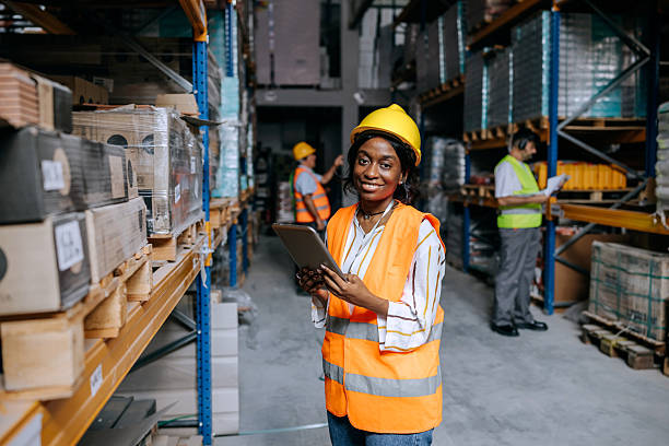istock Young woman posing for camera while using the digital tablet in a warehouse 2225213625
