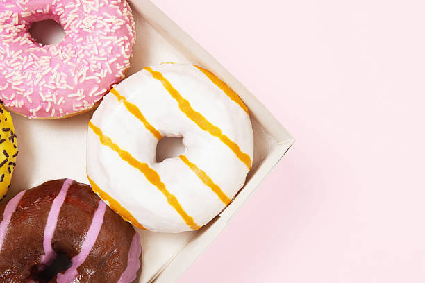 istock Closeup round colored donuts with sprinkles and topping. Glazed doughnut box. Pastel pink background. Donuts with different flavors - caramel, chocolate, gum 2225217383