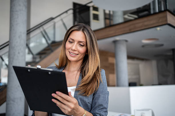 istock Smiling businesswoman reading notes on clipboard in modern office 2225219912